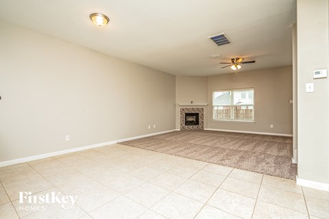 an empty living room with a fireplace and tile flooring