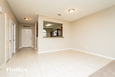 an empty living room with a white tile floor and a white door