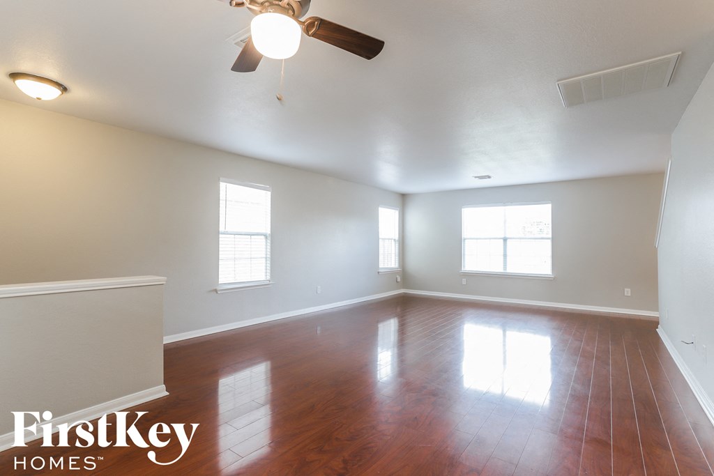an empty living room with wood floors and a ceiling fan