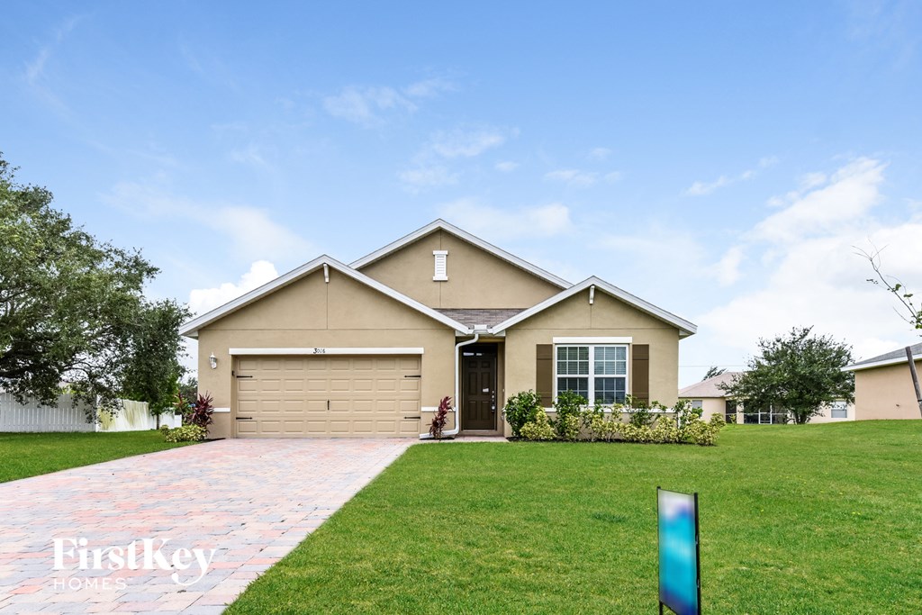 a beige house with a lawn and a driveway