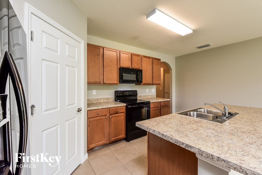 a kitchen with wood cabinets and black appliances and granite counter tops