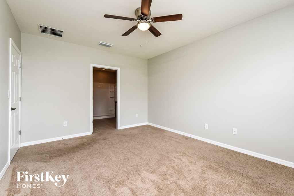 an empty living room with a ceiling fan and carpet