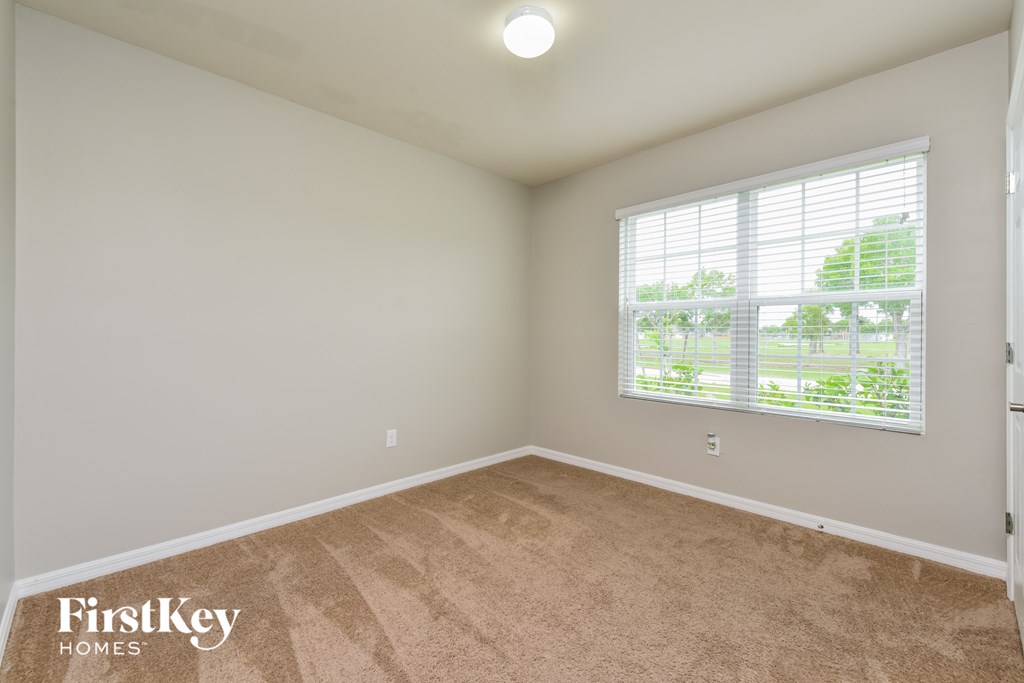 a bedroom with a large window and a carpeted floor
