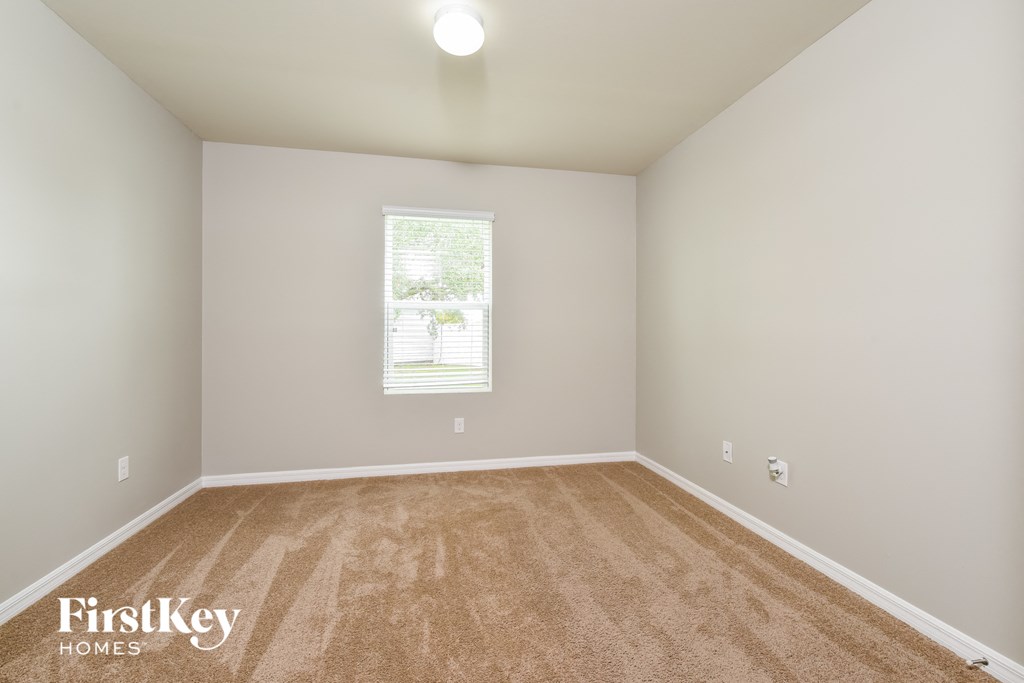 a spacious room with carpet and a window