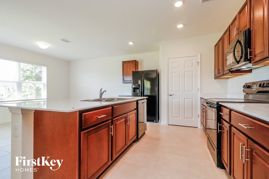 A kitchen with wooden cabinets and a black refrigerator.