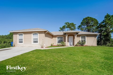 a beige house with a lawn and a driveway