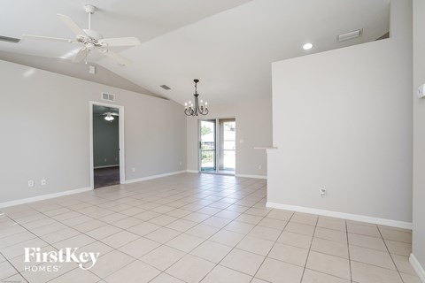 a clean empty living room with a ceiling fan and white walls