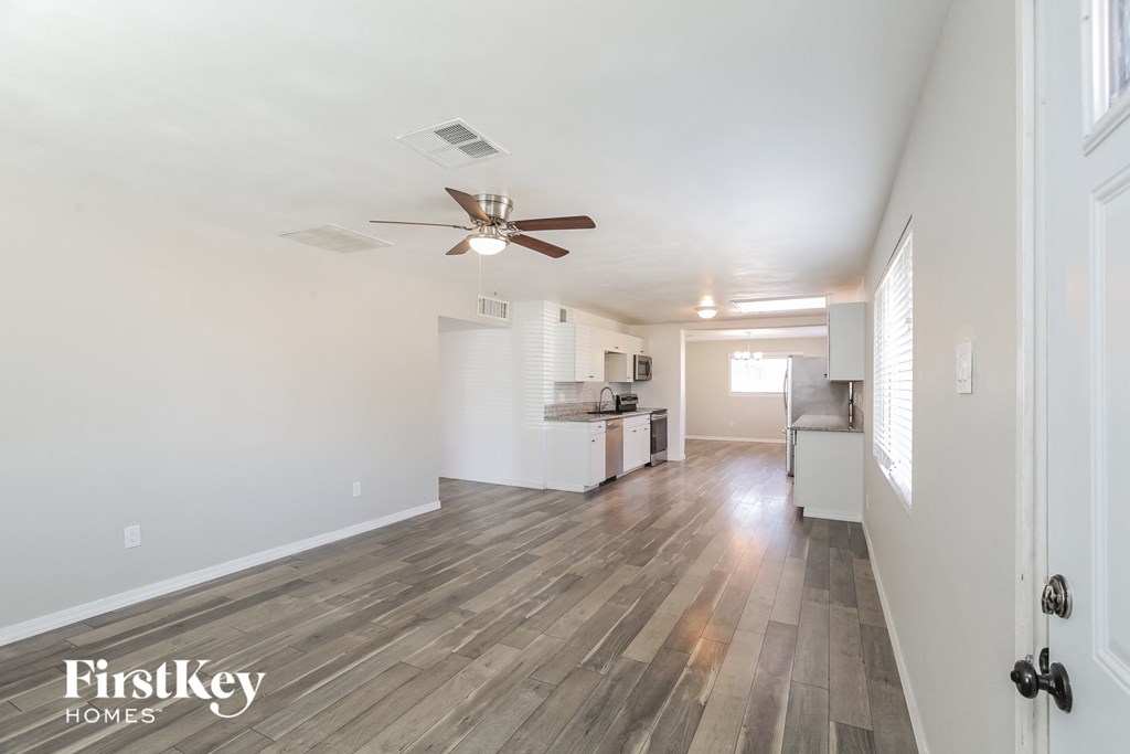 a living room with a ceiling fan and a kitchen