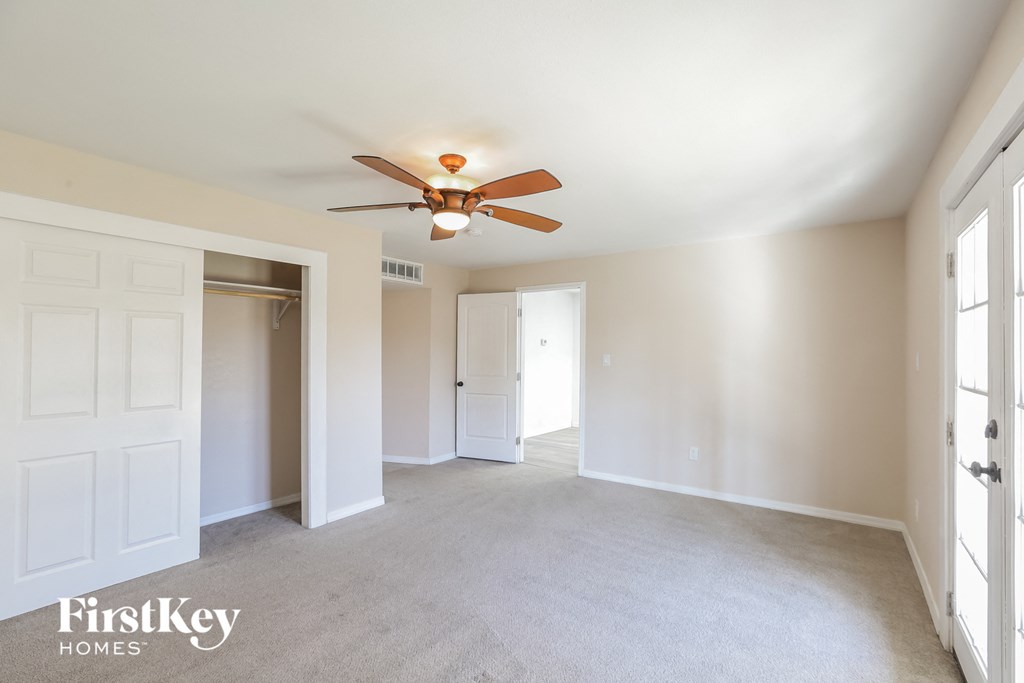 an empty living room with a ceiling fan and a door to a closet