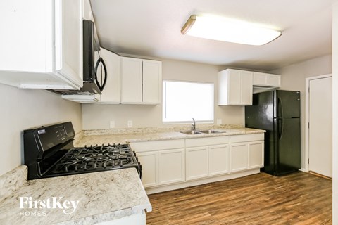 A kitchen with a black stove top oven and a black refrigerator.
