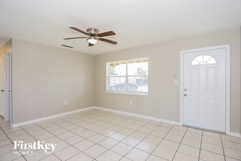 an empty living room with a ceiling fan and a window