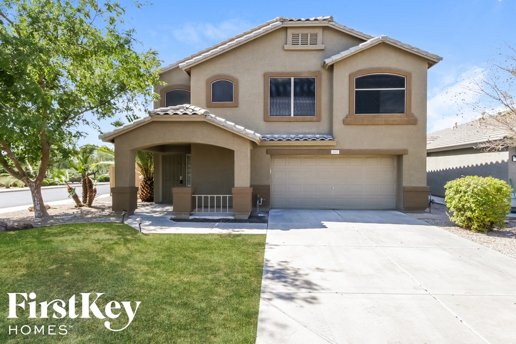 a beige house with a garage and a lawn