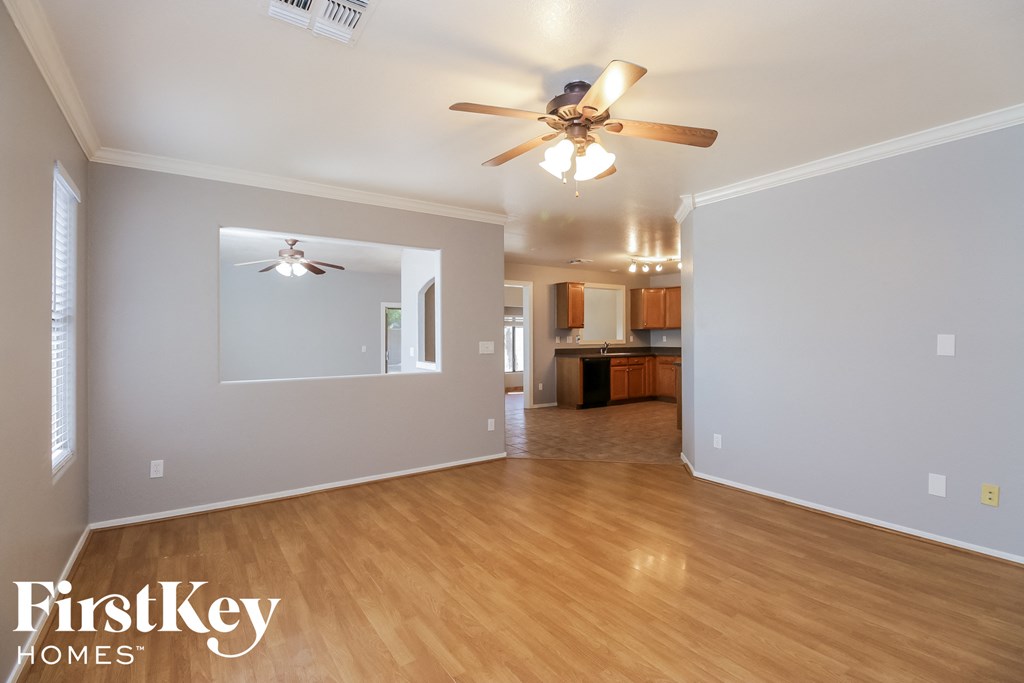 an empty living room with a ceiling fan and wood flooring