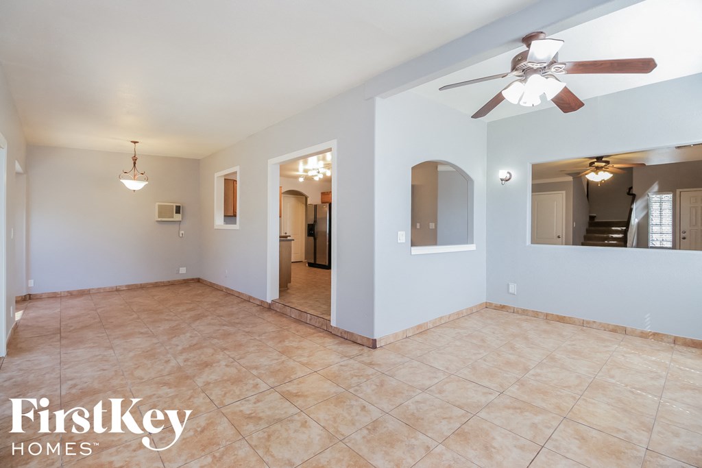 an empty living room with a ceiling fan and a tile floor
