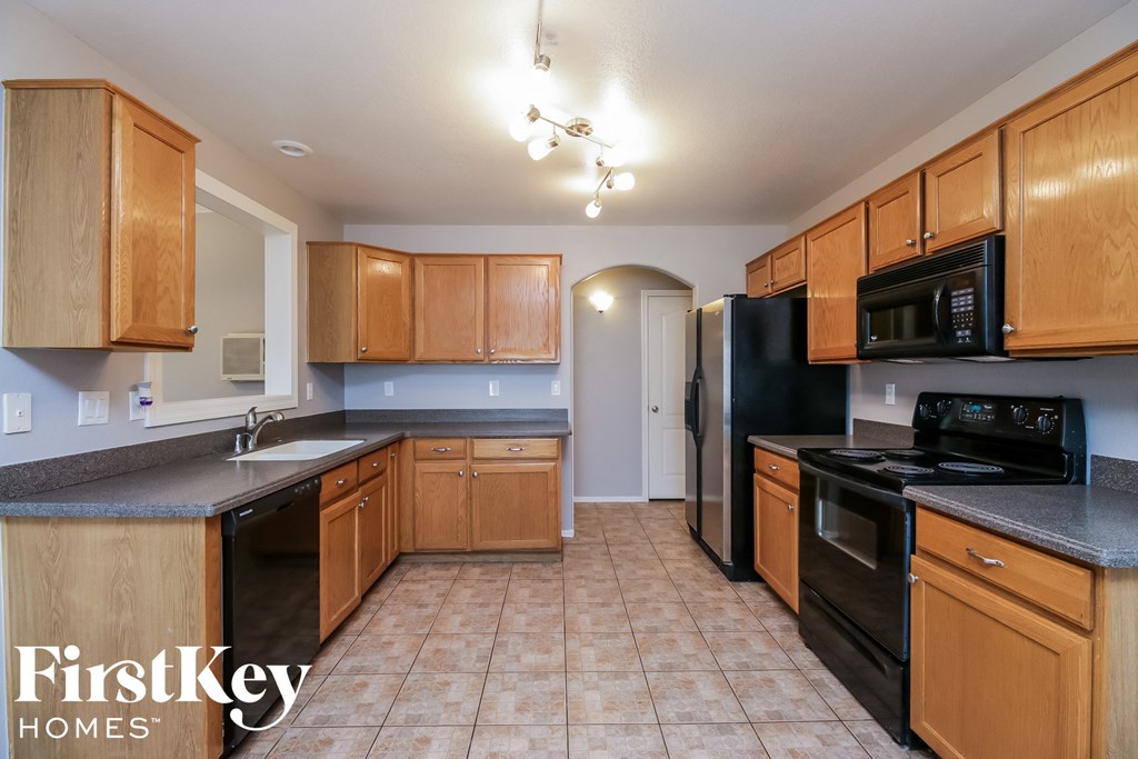 full view of kitchen with black appliances and wood cabinets