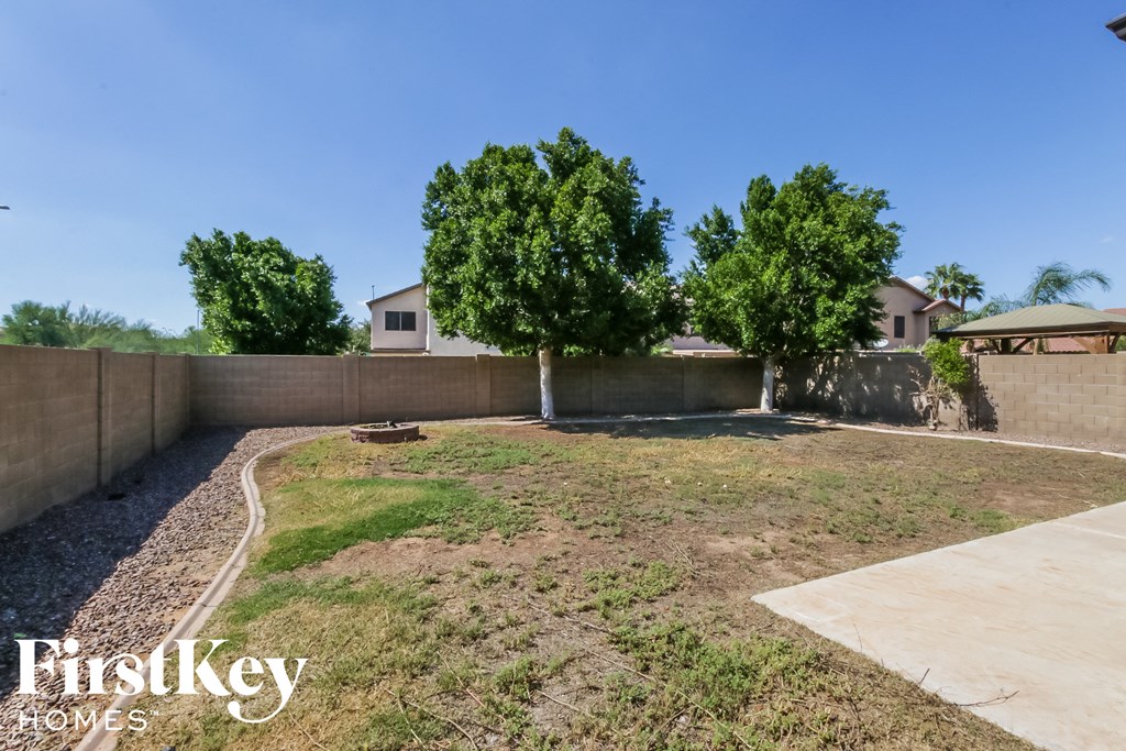 a backyard with grass and trees and a retaining wall