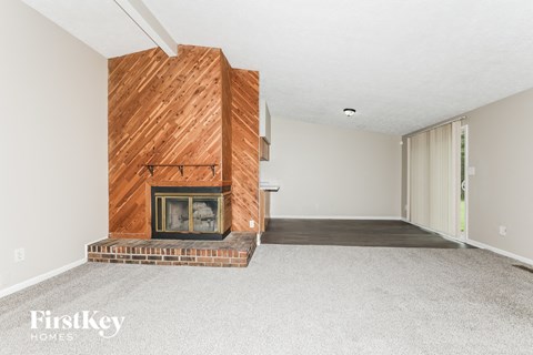 a living room with a brick fireplace and a wooden fireplace mantel and a carpet