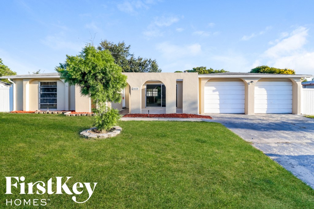 a house with white garage doors and a lawn