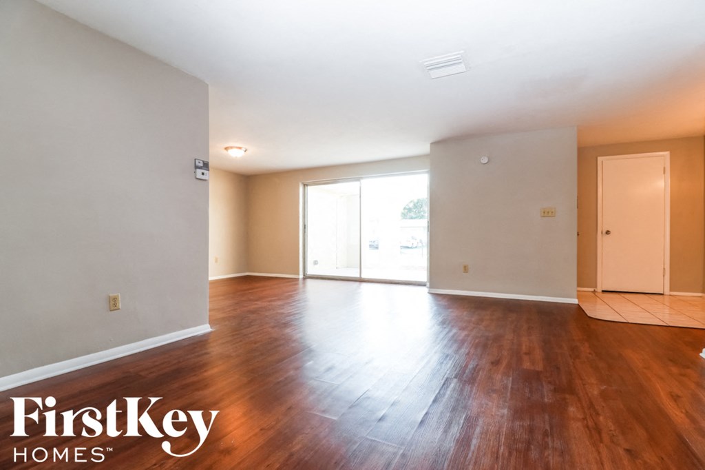 an empty living room with wood floors and white walls