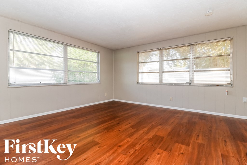 the living room of an empty house with wood floors and windows