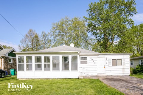 the exterior of a white house with a porch and a driveway