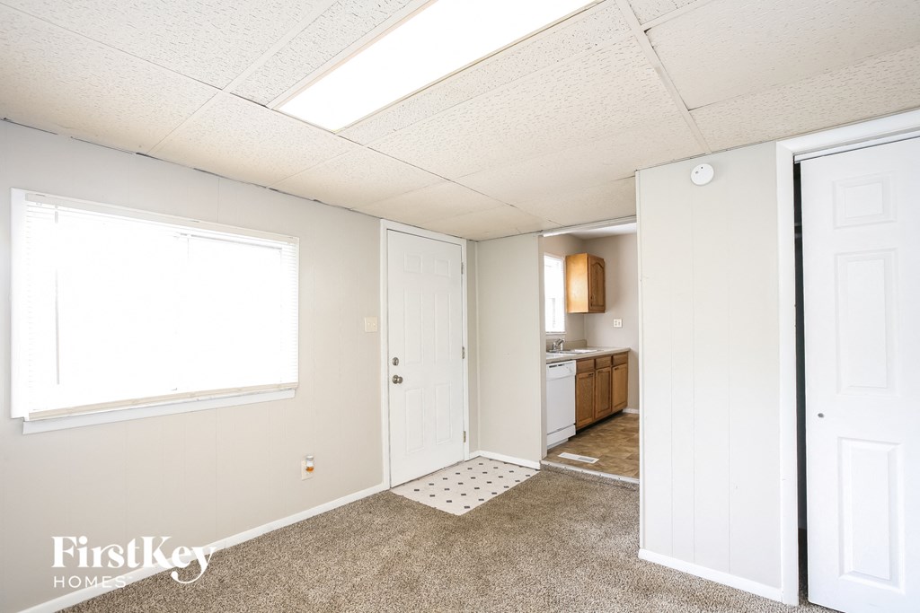 a kitchen with white cabinets and a white door and a window