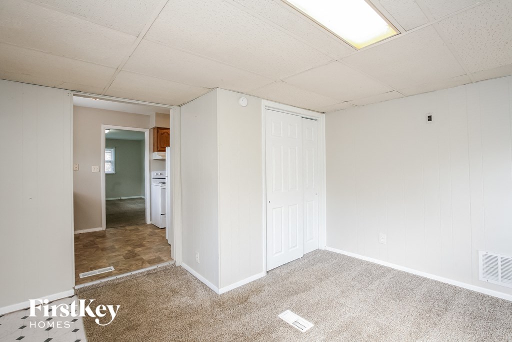 a bedroom with white walls and carpet and a door to a bathroom