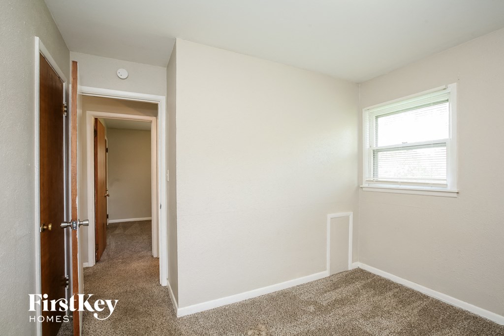 a bedroom with white walls and carpet and a window