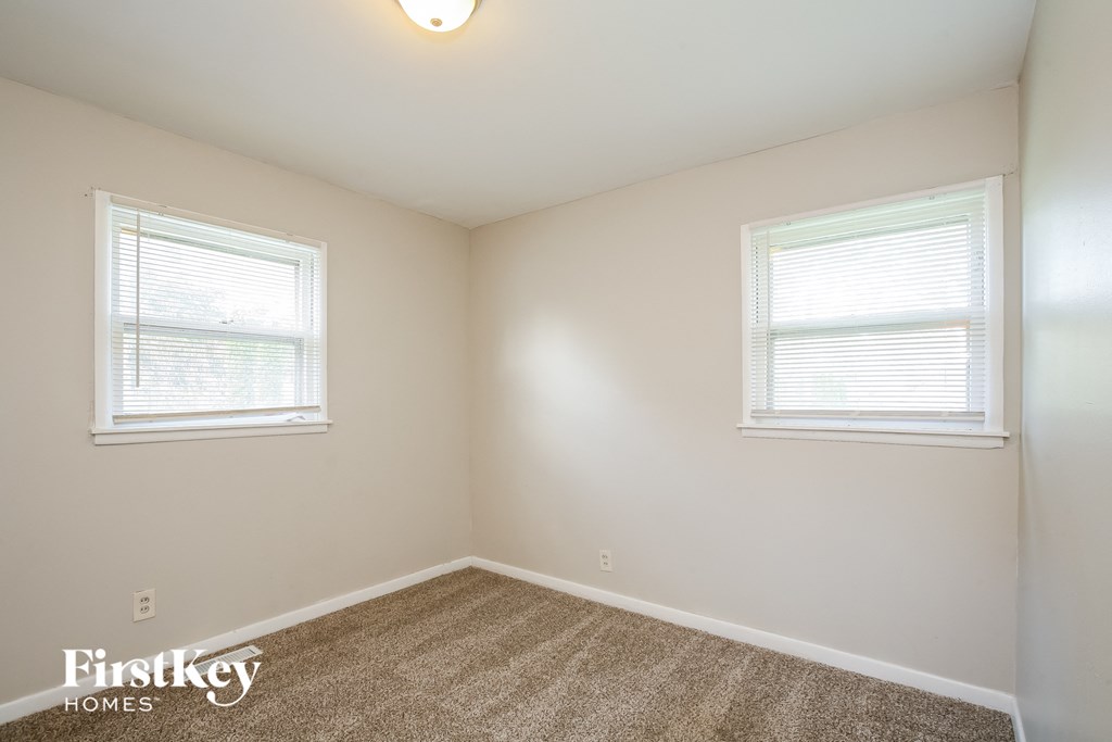 a bedroom with two windows and a carpeted floor
