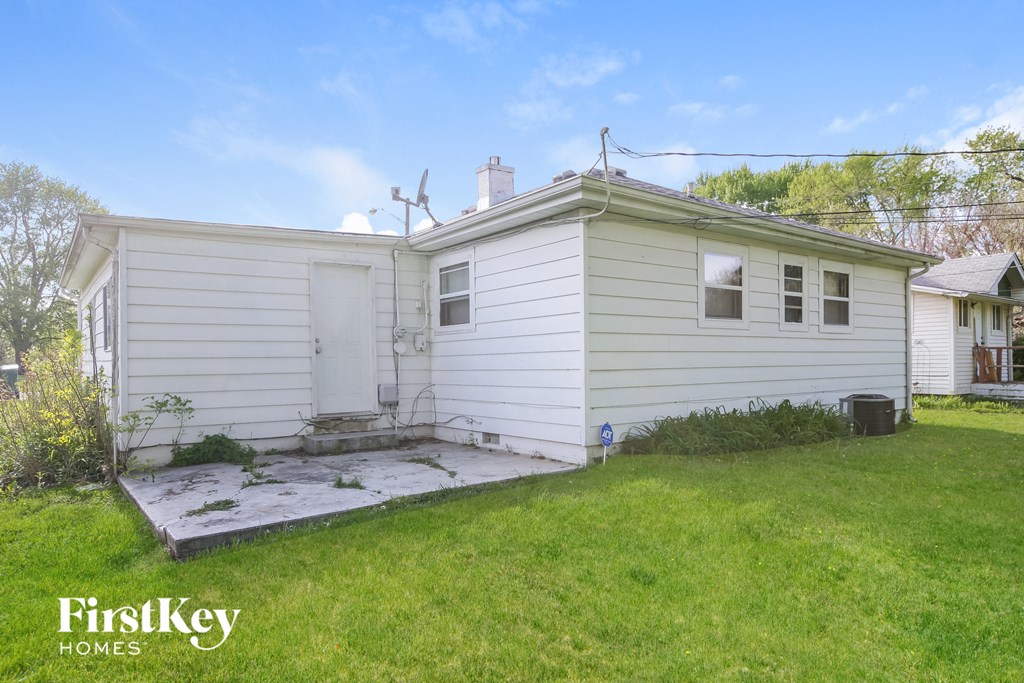the back of a white house with a yard and grass