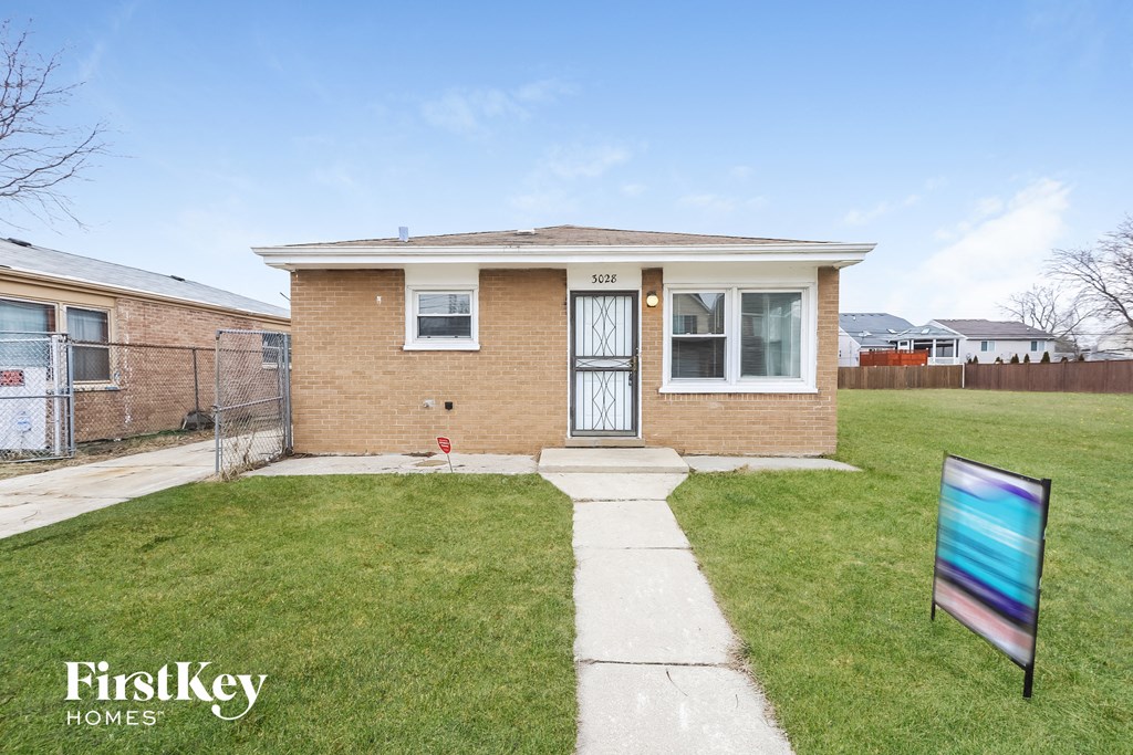 the front of a brick house with a yard and grass