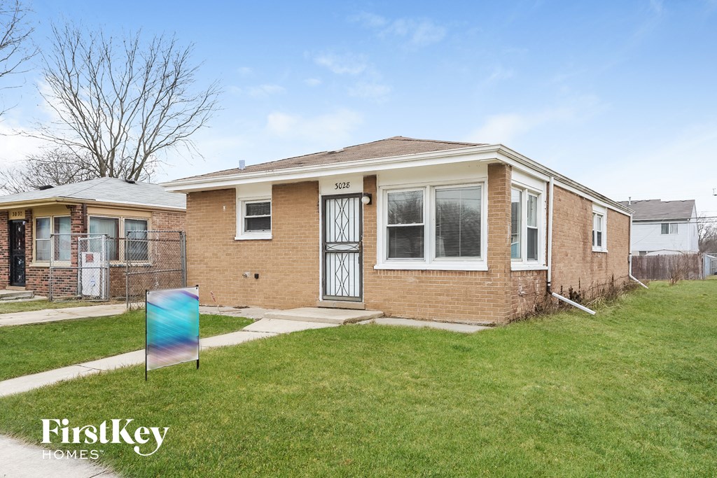 a small brick house with a yard and a sign in front of it