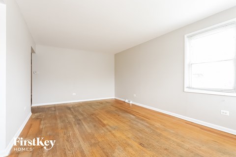 a bedroom with wood floors and white walls and a window