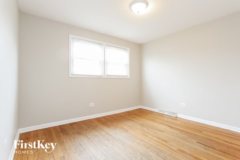a living room with wood floors and white walls and a window