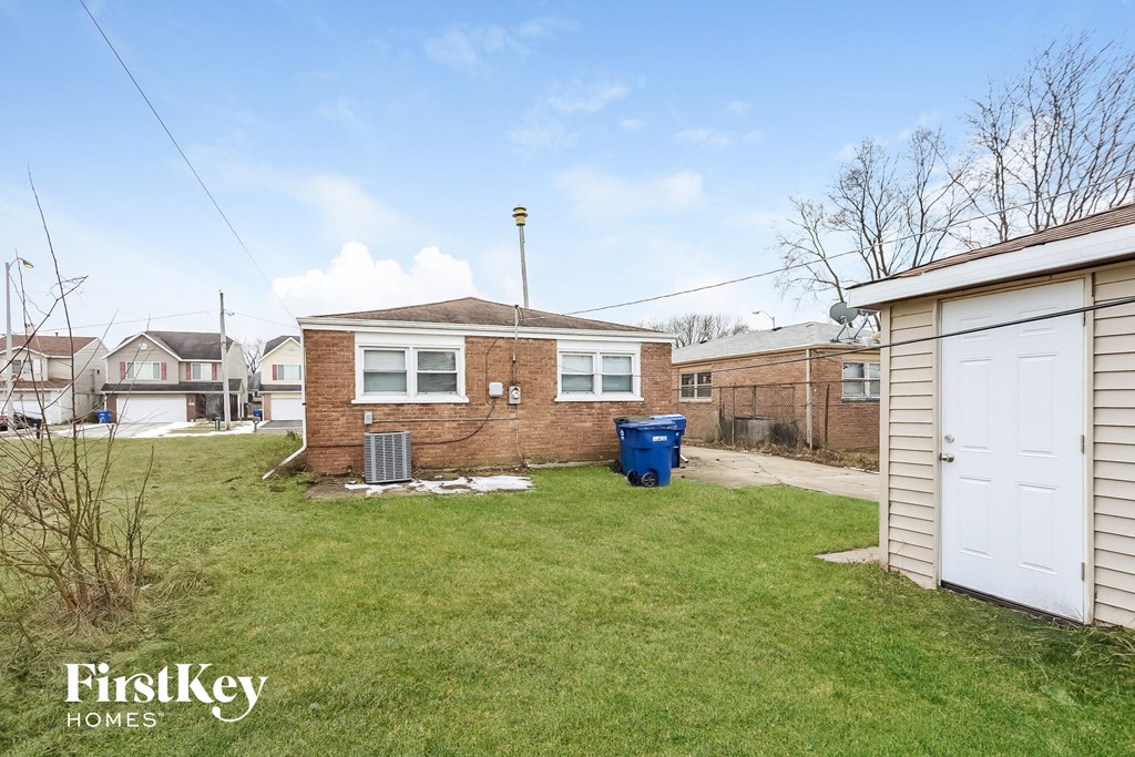 the backyard of a brick house with a yard and a white garage door