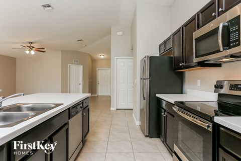 A kitchen with a black fridge and stove and a white sink.