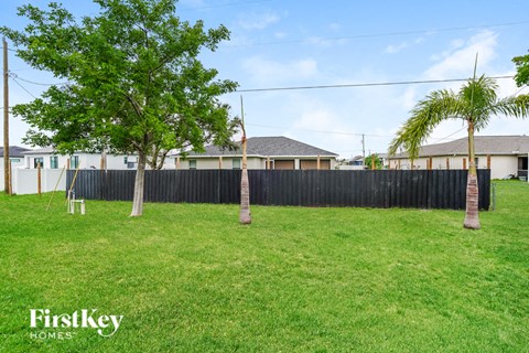 A grassy area with trees and a fence, with the words "FirstKey Homes" on the bottom left.