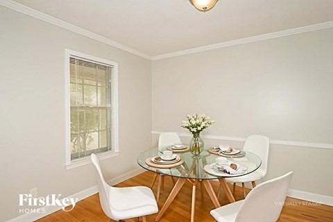 A dining room with a glass table and white chairs.