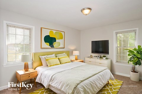 A bedroom with a bed, nightstand, and a painting on the wall.