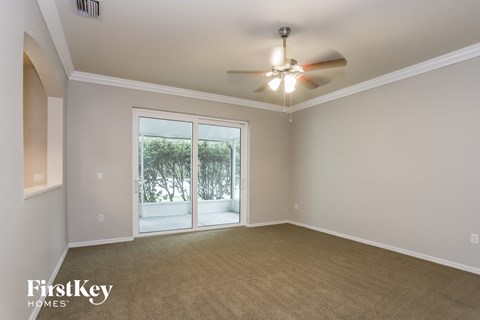 an empty living room with a ceiling fan and a window