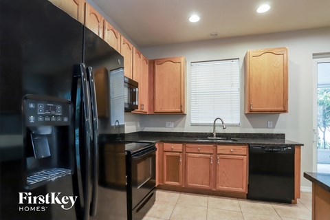 a kitchen with wooden cabinets and black counter tops and black appliances