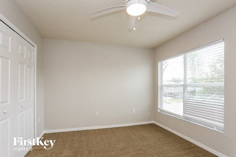 a bedroom with a large window and a ceiling fan