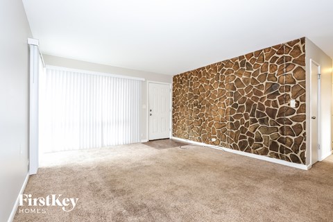 a living room with carpet and a stone accent wall
