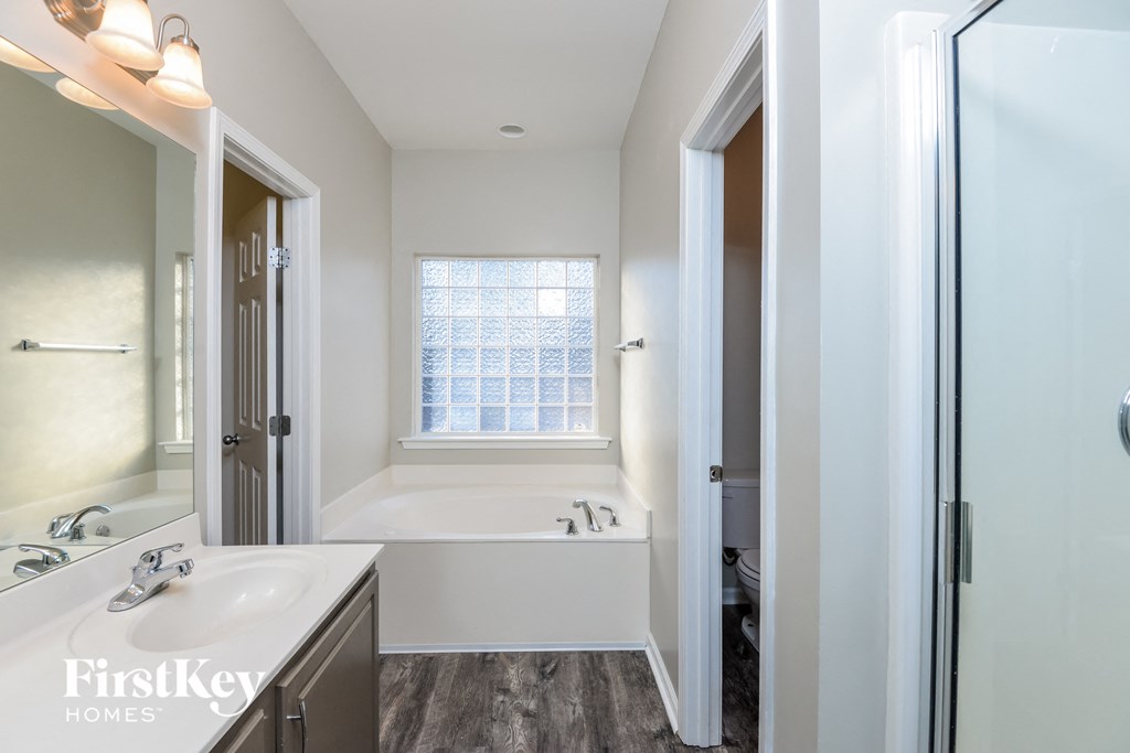 a white bathroom with a tub and a sink and a mirror