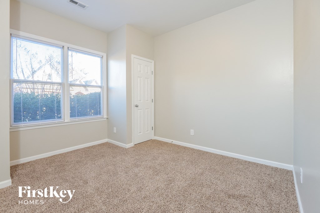 a bedroom with a door and a window and a carpeted floor