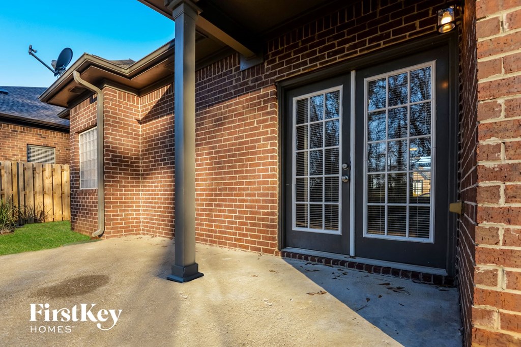 the front porch of a brick house with a driveway and two doors