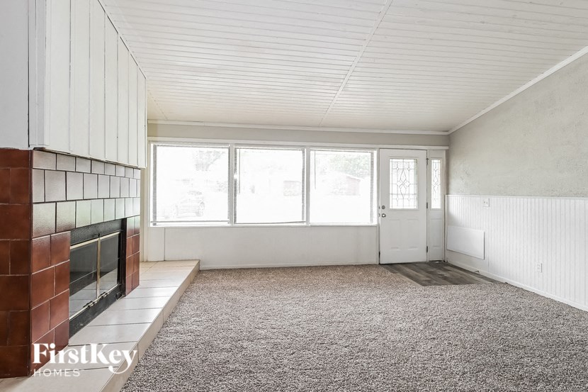 an empty living room with a fireplace and a window