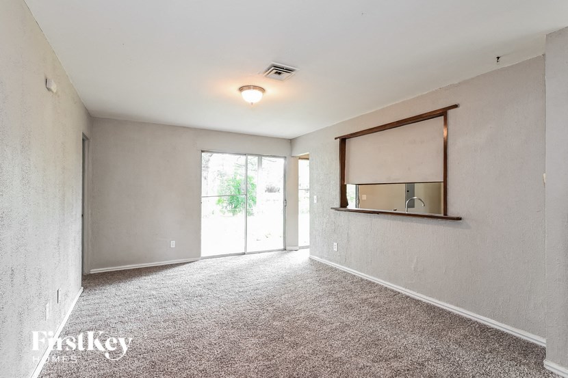 an empty living room with a window and a mirror on the wall