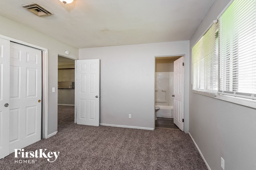 a bedroom with a door to a bathroom and a window