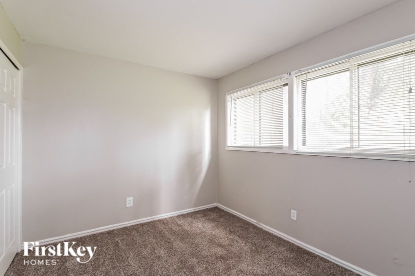 an empty room with three windows and a carpet